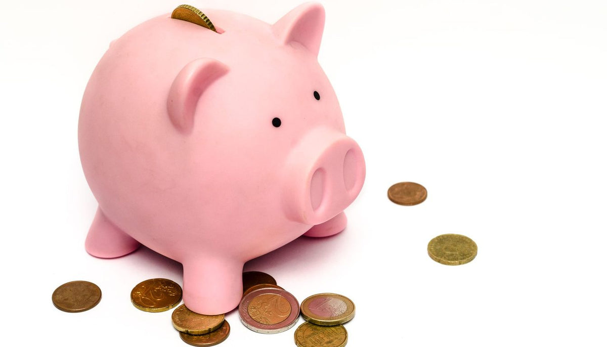 Tirelire cochon rose entourée de pièces de monnaie sur fond clair Image