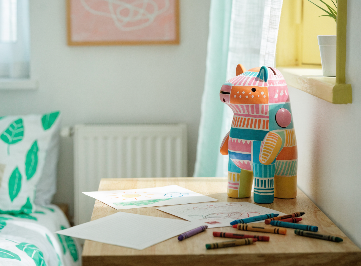 Tirelire animal colorée sur un bureau d'enfant, crayons autour Image
