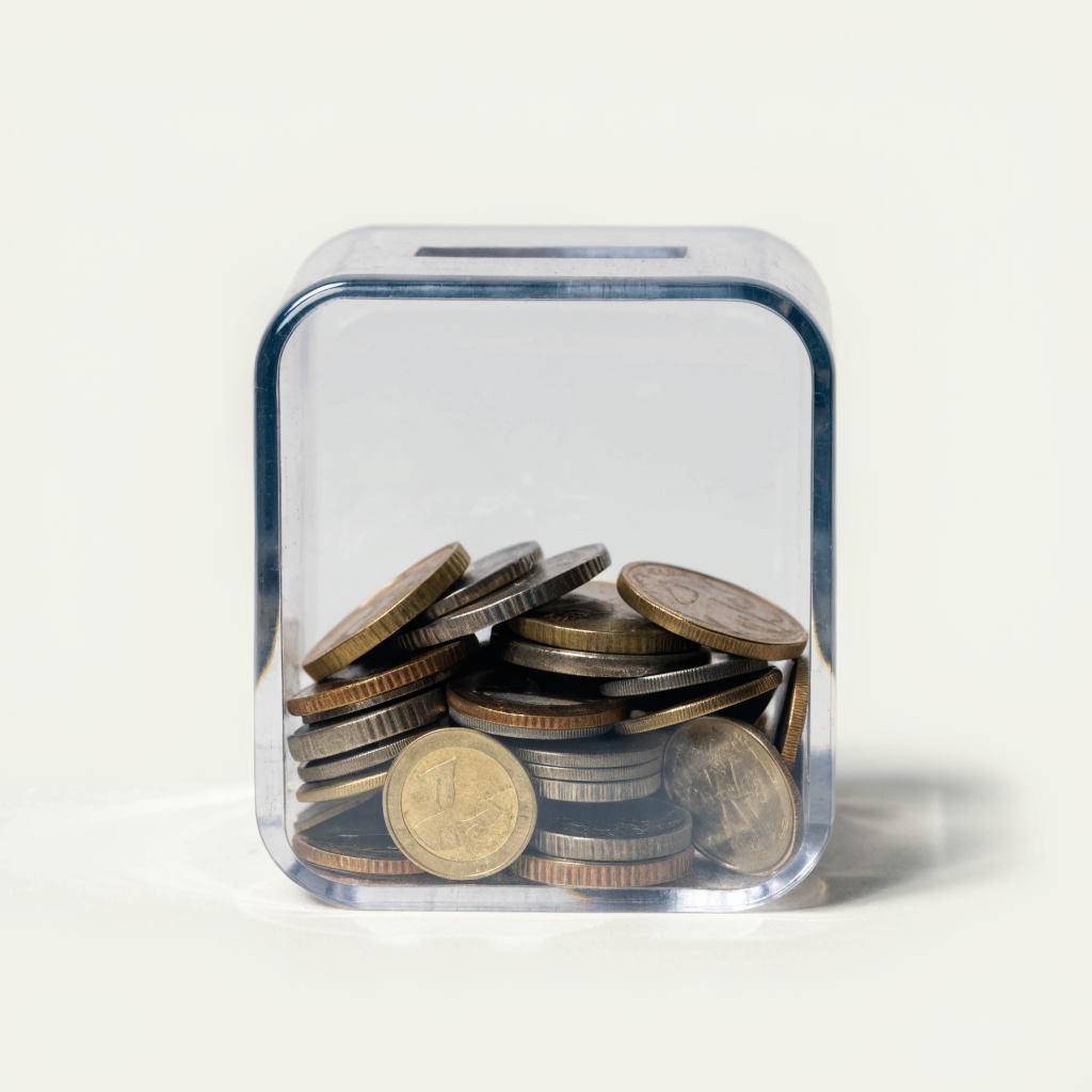 Tirelire transparente partiellement remplie de pièces